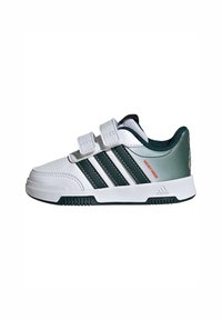 Scarpa da ginnastica bianca con accenti verdi, tre strisce verticali verde scuro e cinturini in velcro. Presenta una parte superiore texturizzata e una suola in gomma con grip.