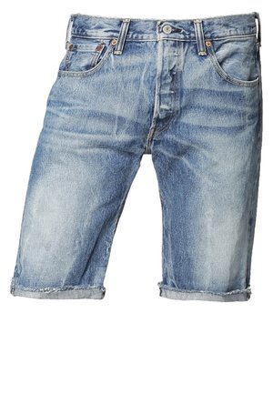 Homme portant une chemise à boutons bleu clair à motifs, un short en jean, des baskets blanches et tenant un sac noir sur son épaule.