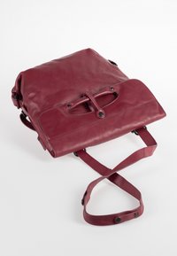 Bordeaux leren tas met een gevouwen ontwerp, verstelbare schouderband en drukknoopsluitingen. Glad oppervlak met een subtiele glans en minimale hardware.
