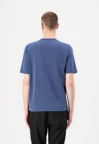 Blue cotton t-shirt with a crew neckline and short sleeves, featuring a relaxed fit and visible stitching details on the hem and sleeves.