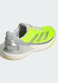 Green and gray athletic shoe with mesh upper, silver accents, textured sole, and three stripes design. Features a reinforced heel and laces.
