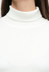 Άσπρο πουλόβερ με ζιβάγκο, κατασκευασμένο από ριμπ πλεκτό ύφασμα. Διαθέτει ψηλό λαιμό και στενή εφαρμογή, με λεία υφή και ελάχιστες λεπτομέρειες.