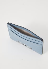 Jasnoniebieski skórzany portfel na karty o teksturowanej powierzchni, z wieloma slotsami na karty oraz subtelnym metalicznym akcentem wzdłuż dolnej krawędzi.