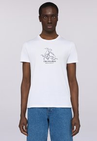 Camiseta de algodón blanca con cuello redondo, que presenta un dibujo a línea negro de perros y el texto "TRUSSARDI GENTLE SOCIETY" debajo. Corte casual.