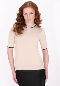Beige rövid ujjú felső, testre szabott fazonnal, tengerészkék bordás gallérral és ujjak végénél. Simaság jellemzi, finom fényességgel.