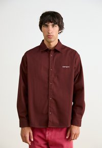 Μαρούλι μακρυμάνικη πουκάμισο, με κουμπιά, φτιαγμένο από ανθεκτικό ύφασμα, διαθέτει γιακά τύπου πιπίλα και λευκό κεντημένο λογότυπο στην αριστερή πλευρά.