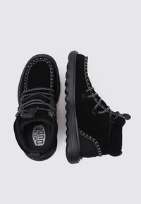 Botas de tobillo de ante negro con suela de goma texturizada, que cuentan con detalles tejidos en la parte superior y cordones en contraste para un ajuste seguro.