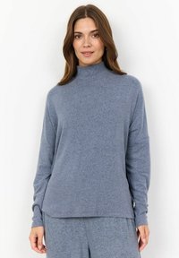 Light blue, long-sleeve mock neck top made of soft fabric with a relaxed fit, featuring a slightly longer back hem and ribbed cuffs.