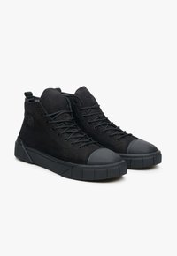 Czarne trampki typu high-top z zamszową cholewką, gumowym noskiem, wzmocnionym piętą i teksturowaną podeszwą. Posiadają okrągłe sznurowadła i detal z logo.