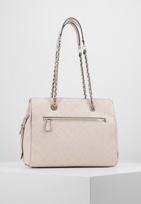 Ljusrosa tygväska med präglat logomönster, dragkedjeförsedd framficka, dubbla kedjeaxelband och slätt syntetmaterial.