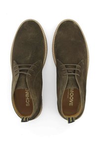 Chaussures en daim marron avec un bout arrondi, un laçage classique et une semelle texturée contrastante. Marque visible à l'intérieur.