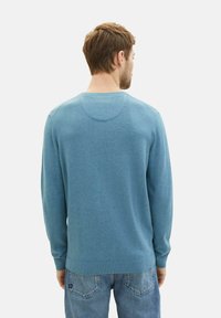 Blauer Pullover aus weichem Strickstoff, mit Rundhalsausschnitt, langen Ärmeln und gerippten Bündchen. Die Rückansicht zeigt eine glatte Textur.