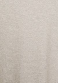 Tissu textile beige avec une surface douce, légèrement texturée et un motif de tissage subtil visible.