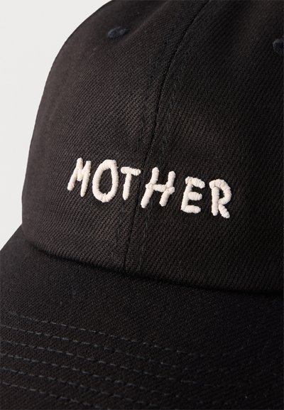 Μαύρο καπέλο μπέιζμπολ με λευκή κεντημένη επιγραφή "MOTHER" στο κέντρο πάνω από τη ρίγα σε υφασμάτινη επιφάνεια με υφή.