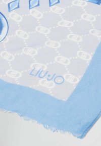 Pañuelo de seda de color azul claro con un patrón de logotipos geométricos, con un borde fringido y un borde sólido azul. El nombre de la marca "LIU:JO" es visible.