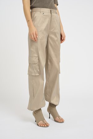 Beige cargo pants featuring a smooth, shiny texture, front pockets, and a wide-leg design, paired with open-toe beige heels.