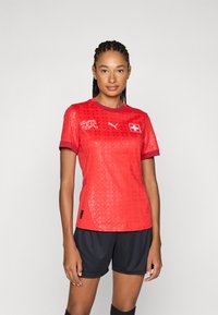 Red soccer jersey with a textured design, circular collar, and purple accents. Features Switzerland flag emblem and Puma logo.