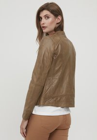 Svetlo hnedá kožená bunda so priliehavým strihom, ktorá obsahuje jemné šitie a hladkú textúru. Zadný pohľad zobrazuje skrátenú dĺžku.