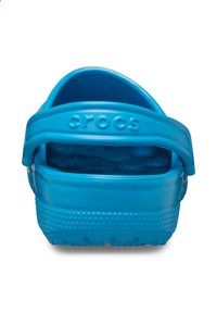 Zuecos azules de Crocs con correa trasera, plantilla texturada y puntos en relieve en la suela, fabricados con material plástico duradero.