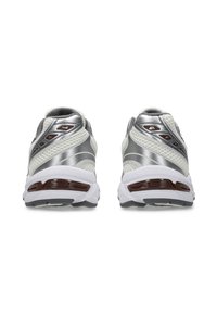 Buty do biegania z szaro-srebrną siateczką, białą, amortyzowaną podeszwą i brązowymi akcentami, zaprojektowane z myślą o komforcie i wydajności.