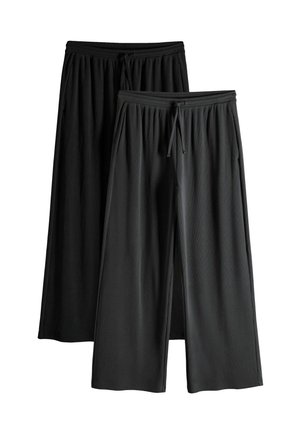 Zwei Paar schwarze Hosen mit weitem Bein, elastischen Taillenbändern und Kordelzügen, eins leicht vor dem anderen auf weißem Hintergrund.