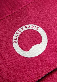Tessuto texturizzato rosa con un logo bianco circolare recante la scritta "DELFSEY.PARIS" stampata in rosso. Il materiale presenta un sottile motivo di tessitura.