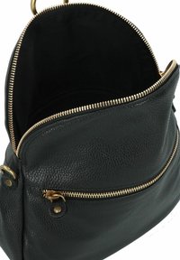 Sac en cuir noir avec une surface texturée, doté d'une fermeture éclair dorée et d'un intérieur spacieux, visible d'une vue de dessus.