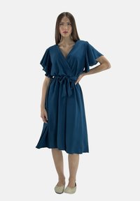 Türkises Wickelkleid mit kurzen schwingenden Ärmeln, einem taillierten Schnitt und einem fließenden Rock. Der Stoff wirkt glatt mit einer leichten Textur.