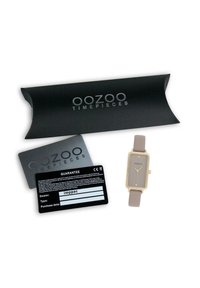 Montre rectangulaire en or avec un cadran gris clair, un bracelet beige, un emballage noir et deux cartes de garantie. Design minimaliste.