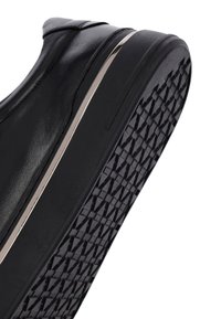 Scarpa in pelle nera con superficie liscia, dettaglio argentato lungo la suola e suola in gomma testurizzata con motivo a rombi.