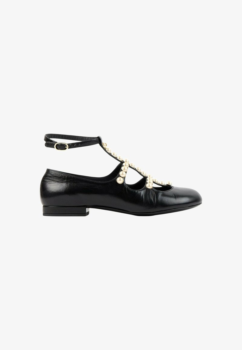 Chaussure plate noire avec bride de cheville et perles décoratives le long de la bride en T et sur les côtés, finition cuir lisse, talon bas.