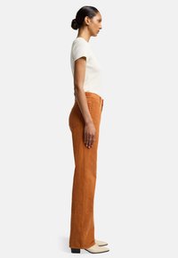 Oranje corduroy broek met een recht model, met een hoge taille, verticale ribbeltextuur en afgewerkt met crèmekleurige schoeisel.