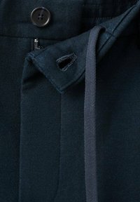 Tissu bleu foncé avec une texture lisse. Comprend une fermeture à bouton et un cordon avec une boucle, mettant en valeur des éléments de design sur mesure.