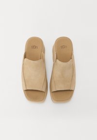 Beige suède instapsandalen met een open teen. Gladde textuur, brede stoffen bovenkant en gevoerde binnenzool. Logo geplaatst op de binnenzool.