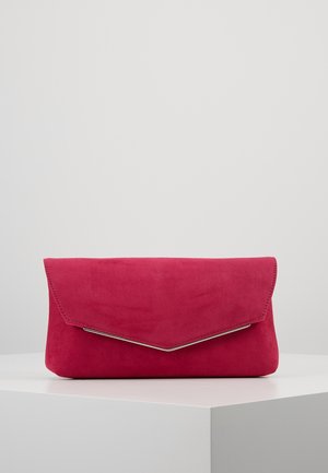 Pochette enveloppe en daim rouge avec rabat géométrique et délicat bord argenté, posée sur un piédestal blanc contre un fond gris uni.