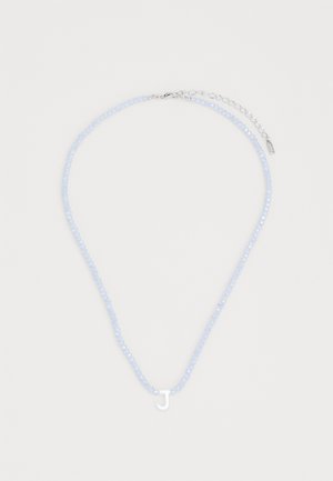 Colier din mărgele albastre deschise, cu un pandantiv alb în formă de literă „J” și un închizător din argint. Dispune de un extensor de lanț pentru ajustarea lungimii.