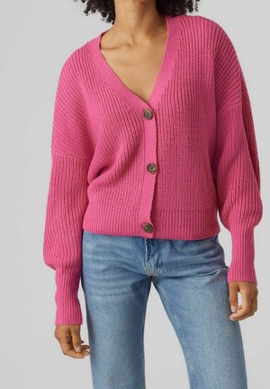 Kirjava vaaleanpunainen neulepaita, jossa on V-pääntie, ylisuurta mitoitusta ja kolme suurta puupainiketta. Ribbatuet hihat ja helma. Rentoa tyyliä.