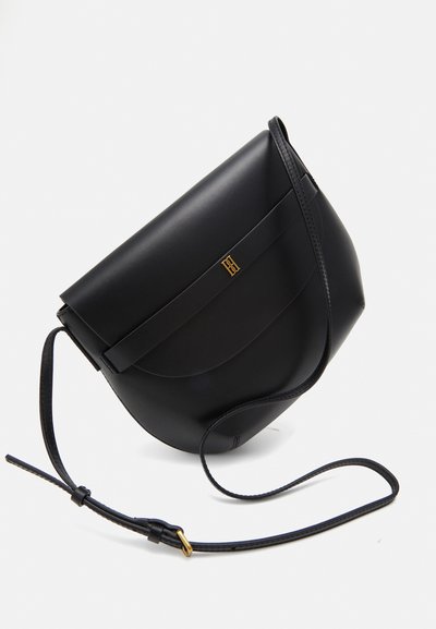 Sac en cuir noir en bandoulière, forme courbée, sangle unique réglable, quincaillerie en accents dorés, texture lisse, design minimaliste.