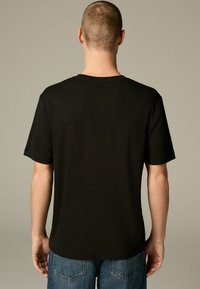 Sort bomuld T-shirt med korte ærmer og rund halsudskæring, med en glat tekstur og en lige skæring ved kanten.