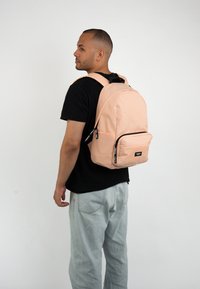 Zaino pesca con tessuto liscio, forma arrotondata, tasca frontale con zip e cerniere nere. Spallacci regolabili e logo sulla parte anteriore.