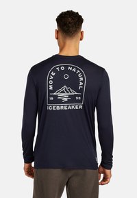 Camicione a maniche lunghe di colore blu navy in tessuto leggero, con una grafica di montagna e la scritta "Move to Natural Icebreaker" sul retro.