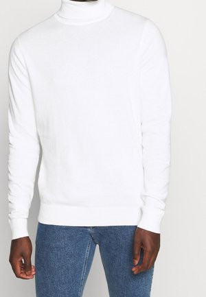 Weißer Rollkragenpullover aus weichem Strickstoff mit langen Ärmeln und enganliegenden Bündchen, kombiniert mit blauen Jeans.