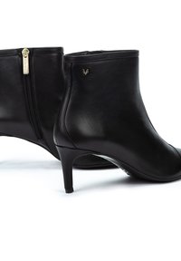 Bottes de cheville en cuir noir avec un design épuré, bout pointu et talon effilé. Présente une fermeture éclair latérale et des accents en métal doré.