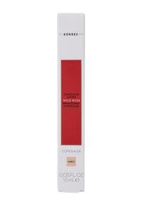 Packaging del correttore illuminante in bianco con un'etichetta rossa audace. Accenti dorati con il nome del prodotto e i dettagli in testo nero. Dimensione: 0,05 fl. oz.