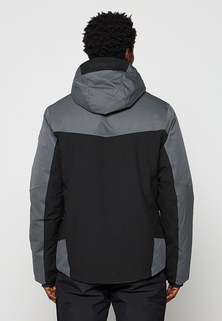 Persona con cabello rizado corto que lleva una chaqueta con capucha en tonos negro y gris, vista desde atrás.