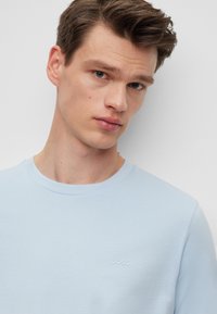 Γαλάζιο T-shirt κοντό μανίκι φτιαγμένο από μαλακό ύφασμα, με στρογγυλή λαιμόκοψη και μικρό ανάγλυφο λογότυπο "BOSS" στο στήθος.