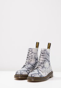 Stivali lace-up con motivo in pelle di serpente grigia, dalla punta rotonda, con lacci grigi e pistoni gialli e neri, montati su una suola in gomma testurizzata.