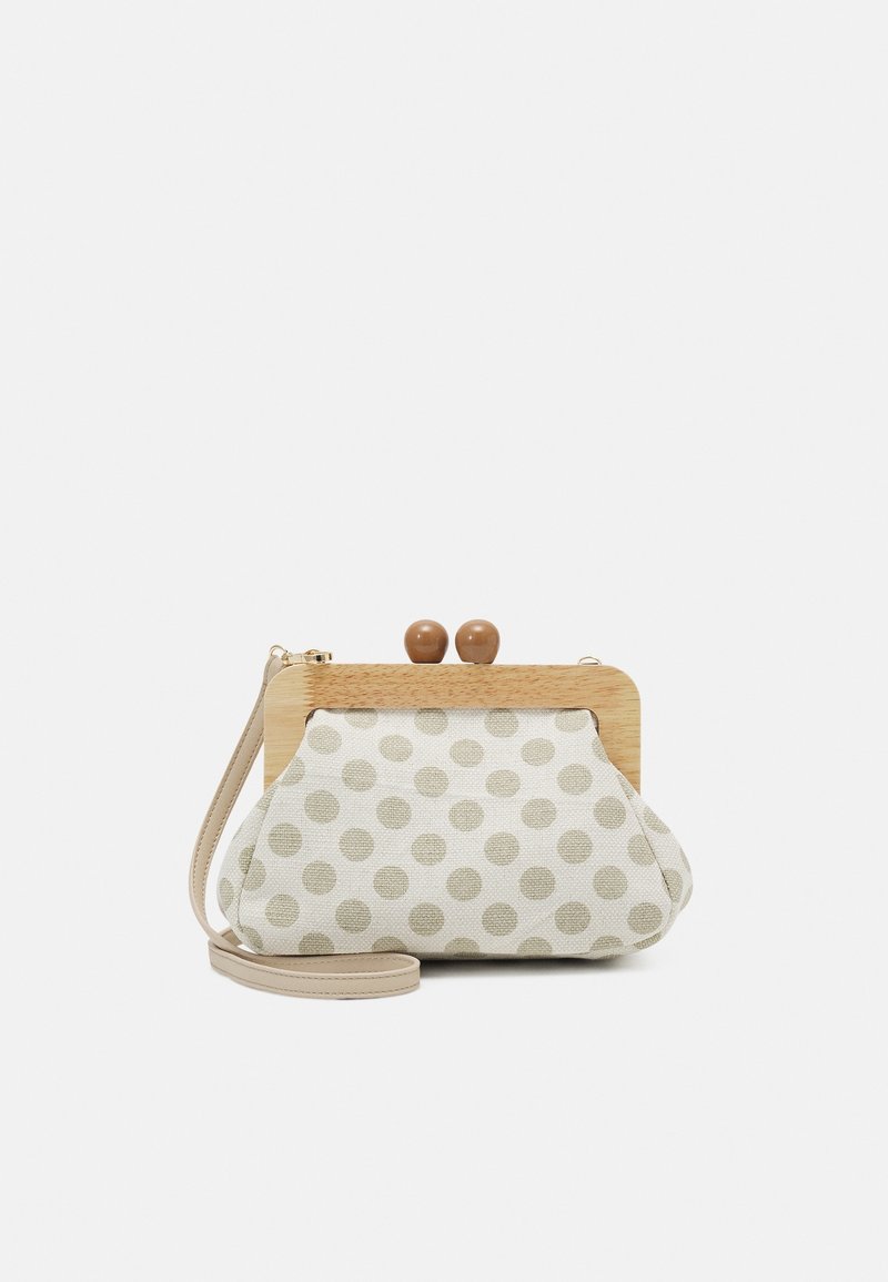 Pequeño bolso de tela beige con lunares marrón claro, cierre de marco de madera y correa para la muñeca sobre un fondo blanco.