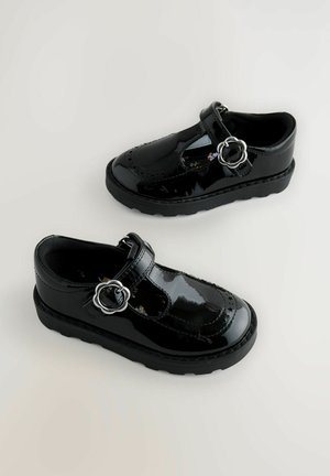 Zwarte gepatineerde leren schoenen met een ronde neus, T-band ontwerp, zilveren ronde gesp en een gestructureerde zool. Gladde afwerking en decoratieve stiksel.