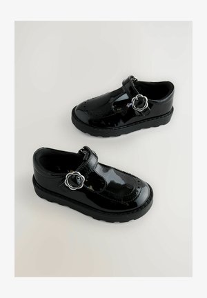 Fekete lakkozott bőrcipők lekerekített orral, T-pántos kialakítással, ezüst színű kör alakú csattal és texturált talppal. Simára polírozott felület és díszvarrás.